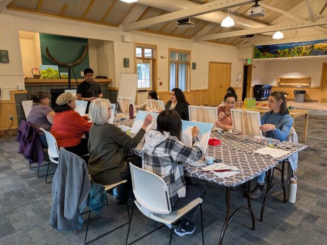 Adults paint on canvasses during an art workshop
