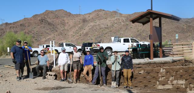 Workers stand nest to partially repaired retaining wall.