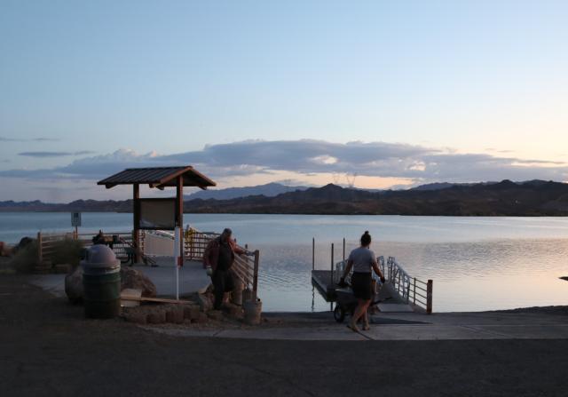 Two workers survey the work area with a lake in the background in the early morning.