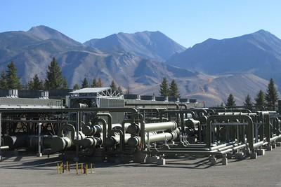 A geothermal plant in front of large mountains. 