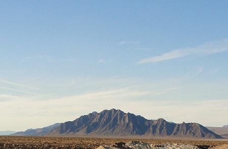 A small mountain range rises from a desert floor.