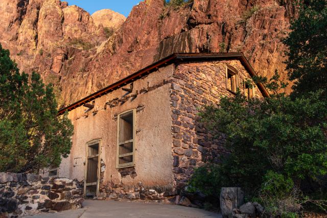 An old stone building near a canyon wall.