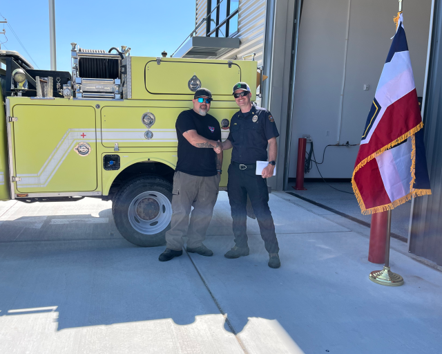 Pila Malolo, WDD AFMO, and Dan Walton, Tooele County Fire Warden, shake hands in front of a Type-6 engine.