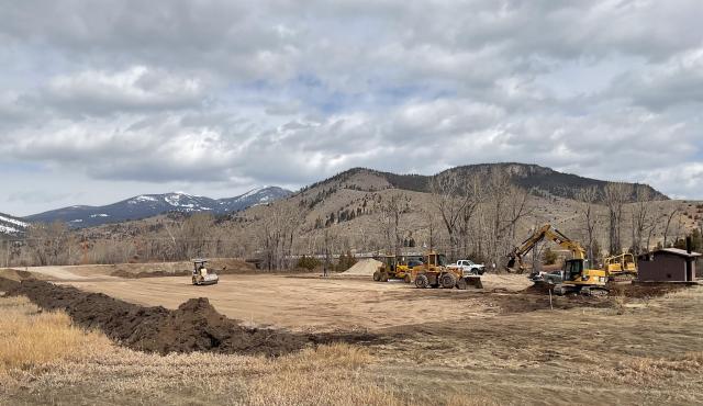 Construction equipment in a flat open space adjacent to some mountains.