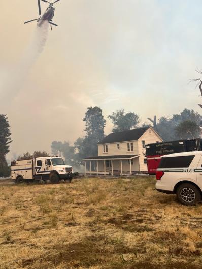 A helicopter drops water near the ranch house.