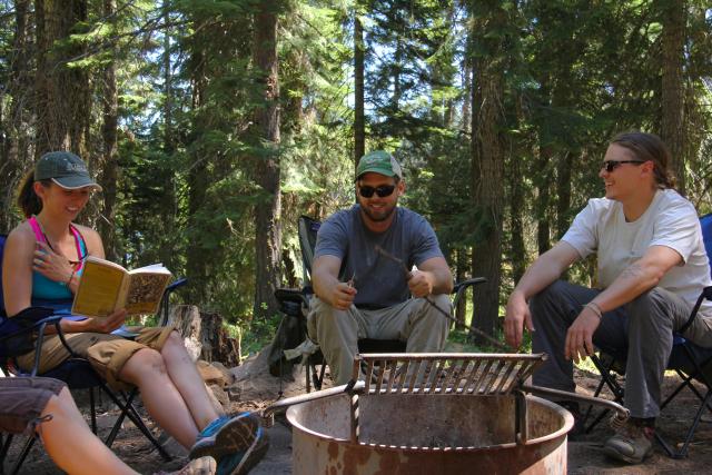 People sit around a campfire ring