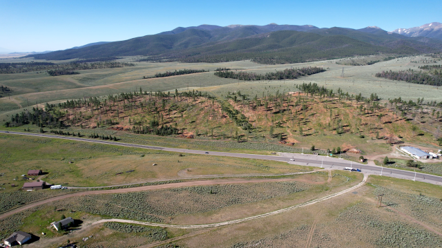 This is Poncha Pass. The roadway and power lines in this photo make up the main transportation and energy transmission corridor serving the San Luis Valley. The land pictured here straddles two counties. It includes both private and public land, which falls under the jurisdictions of both the Bureau of Land Management and the U.S. Forest Service. Photo by Amy Bulger, courtesy of the Colorado State Forest Service