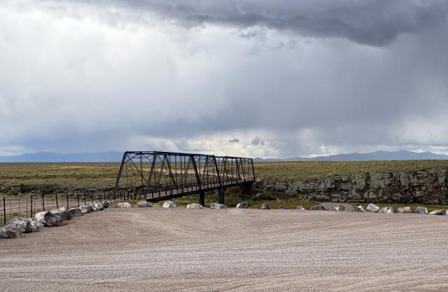 gravel parking lot with view of the historic lobatos bridge which is a metal bridge