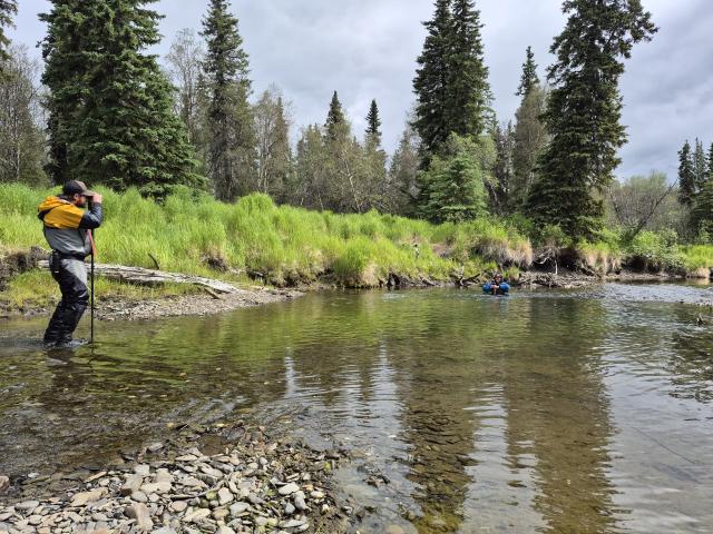 Two scientists collect stream data in Alaska.