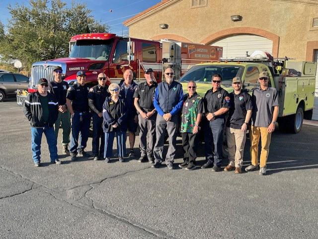 A group of people pose for a photo in front of a fire engine.