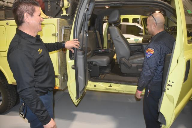 Two men look inside a fire engine cab.