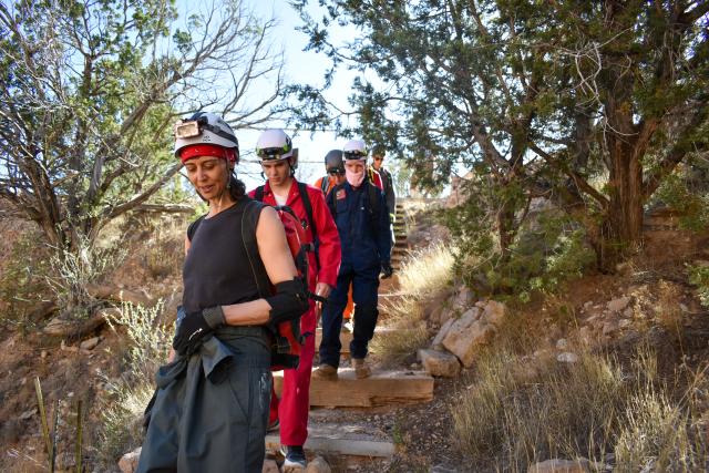 A woman is leading a group of five people down stone steps. 