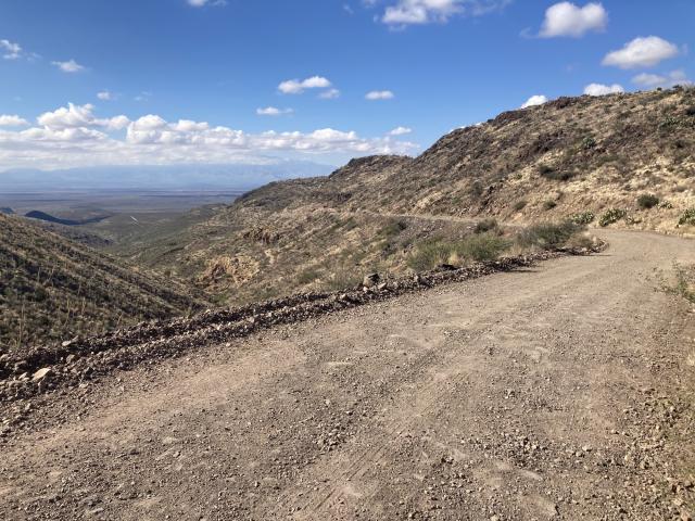 A gravel road passes through a scenic area with mountains