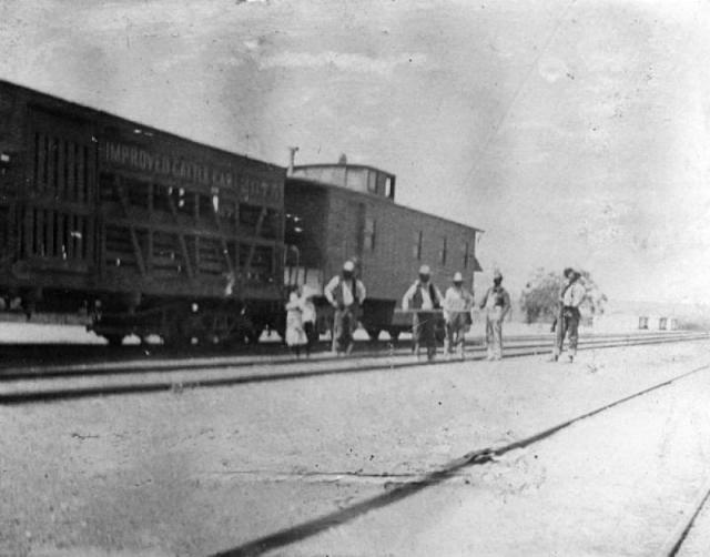 A black and white photos of a train with several men standing near it