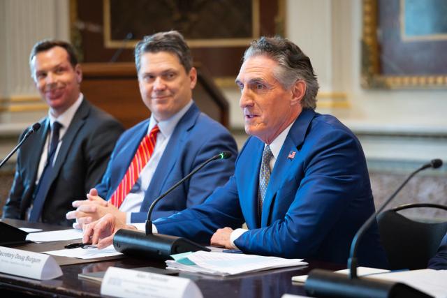 Secretary of the Interior Doug Burgum sits at a table with two other staffers at a listening session with leaders of outdoor recreation and conservation groups at the White House.
