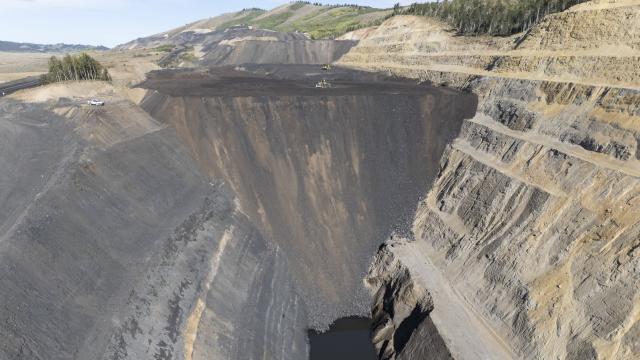 Phosphate mining in Idaho with rock wall, and hill on left.