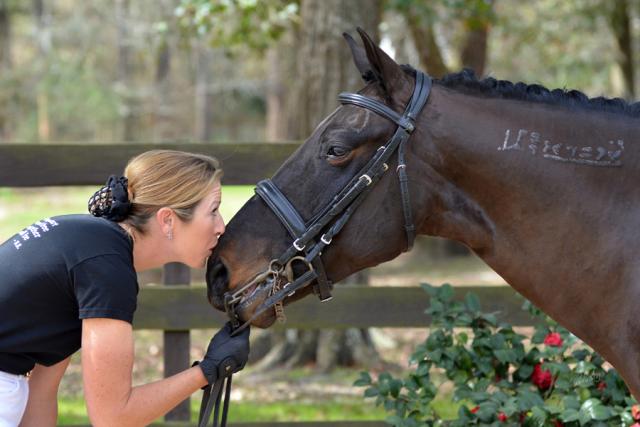 Women kisses nose of horse. 