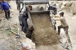 BLM volunteers in Texas dump dirt out of a small tilt-bed truck