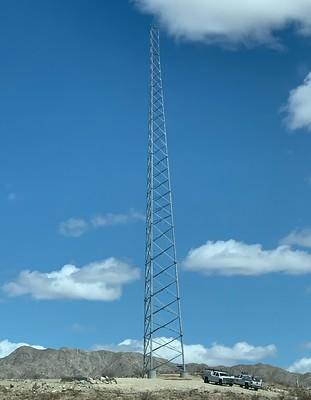 A tall communications tower rises over a desert landscape.