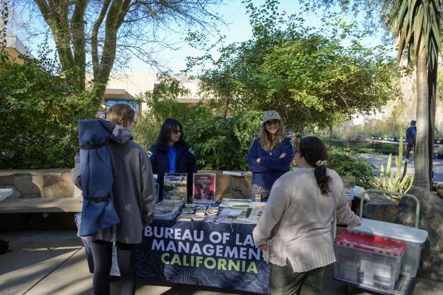 a group of blm staff talk to patrons at a booth.