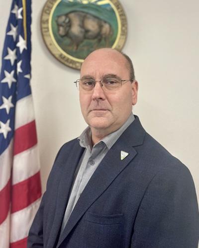 portrait of a person with glasses standing next to a flag