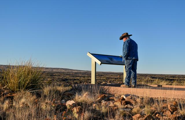 A visitor to the Valley of Fires Recreation Area reads a new interpretive sign at the start of the Malpais Nature Trail on Jan. 16.