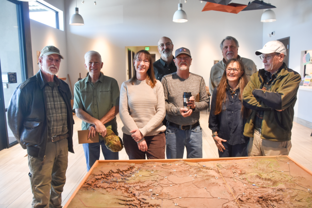 A group of people stand behind a relief map