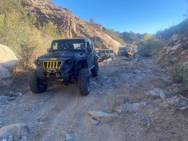 A black Jeep traverses a rough road.