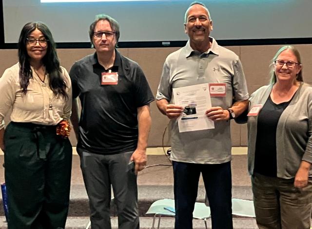 A group of two men and two women stand together. One of the men, a volunteer, holds a pass in his hands.