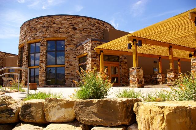 A circular stone building and large wooden shade structure