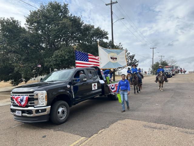 Group of people walking beside a truck decorated with US flags and bunting