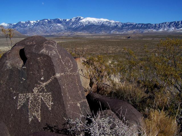 A petroglyph atop a hill with a mountain in the background.