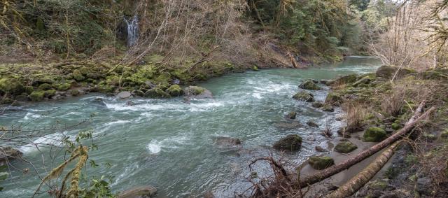 Riverside view at the Sixes River Recreation Site, with small waterfall in the background