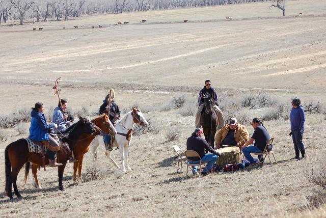Singers in the drumming circle, flanked by riders begin the ceremonies commemorating the battle, originally fought on March 17, 1876. The actual battleground is visible in the distance.
