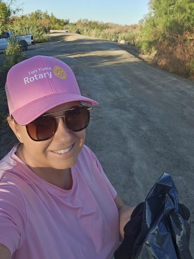 A selfie of a volunteer in a pink hat and shirt in front of the area they just cleaned up.