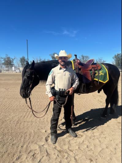 Ranger Nelson Benavidez stands with BLM mustang. Photo by DOI. 