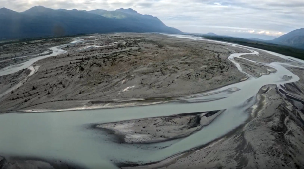 Braided river flowing through a valley with mountains on either side.