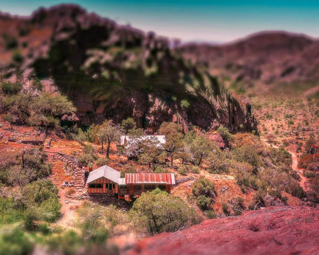 A group of abandoned buildings at the base of a cliff.