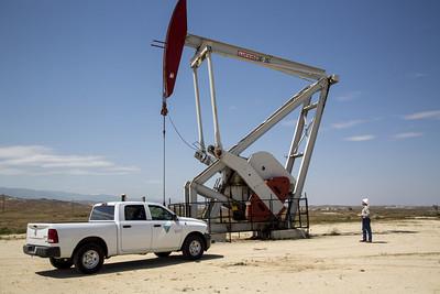 AA white pick up truck parked next to an oil derrick