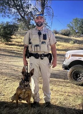 A uniformed officer poses with a dog.