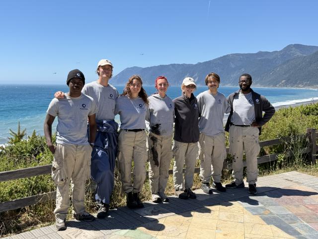 A line of volunteers posing in front of the Pacific Ocean.