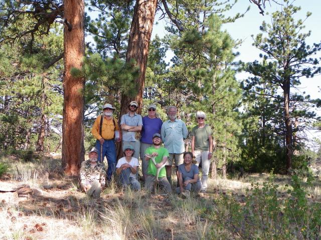 a group of people pose for a photo in a forest