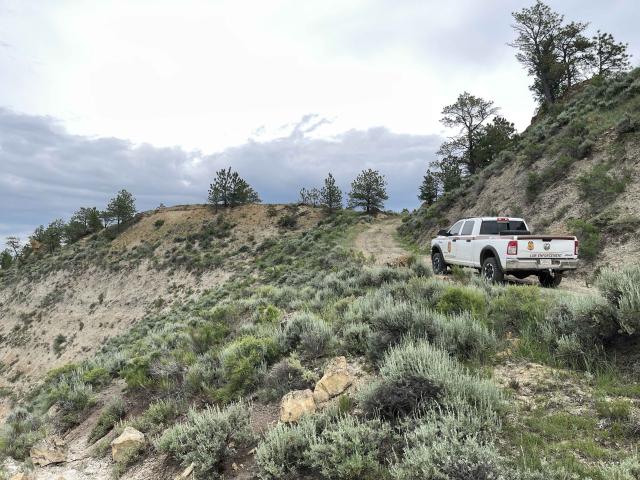 Law enforcement vehicle on a dirt road with mountain landscape 