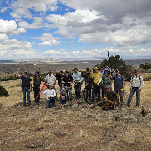 Volunteers and Staff pose for a group photo with 17 people total after removing the old fence from the land.