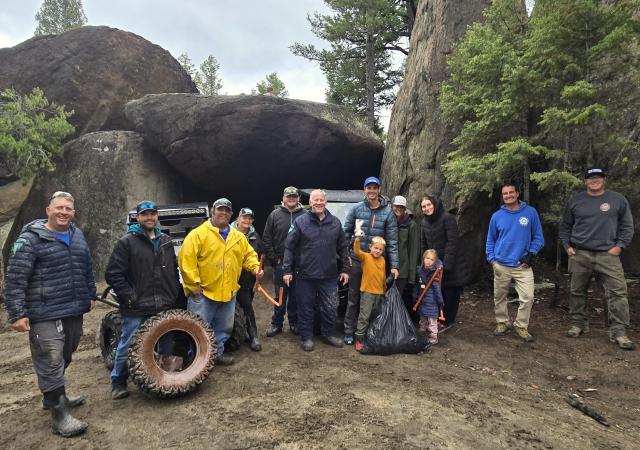 A group of people pose for a photo surrounded by trees and large boulders