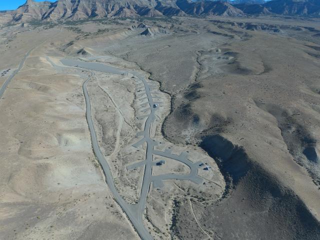 An aerial view of a treeless desert campground featuring a couple dozen paved parking pads