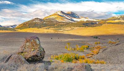 A snow peaked summit and a large rock.