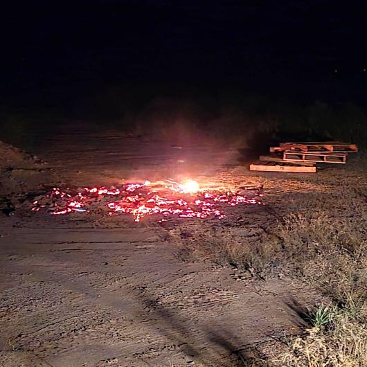 A smoldering bonfire next to some stacked pallets