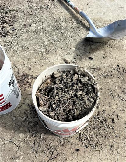 A white 5-gallon bucket full of nails and debris