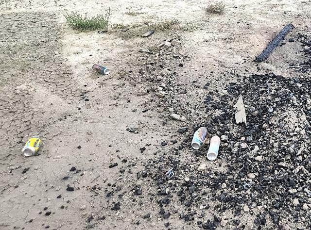Empty cans and burned debris litter the ground